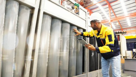 Männlich Techniker Ingenieur mit Helm hält Tablette inspiziert den Arbeitsplatz speichert Sauerstofftanks Drucktanks und überprüft Sicherheit Arbeitsdruck sicheren Lagerbereich in der Blechindustrie Fabrik.