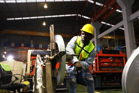 Black african american male worker works roof sheet metal rolling machine at high speed when accident suddenly causes his arm to get locked into the steering wheel causing his arm to break in pain.