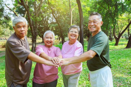 Cheerful group asian elderly retired people who are in good health join hands together join forces recreational activities play sports exercise have fun in the morning have good mood live long life.