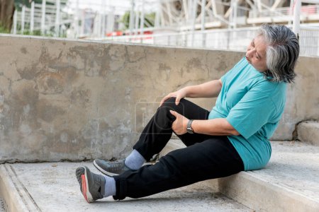 Téléchargez les photos : Asian elderly woman is currently having a knee injury during her exercise by running in the stairs, due to osteoarthritis, to sports and health care concept. - en image libre de droit