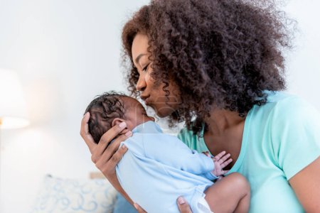 Foto de Una madre afroamericana besando frente a su hijo recién nacido de 1 mes de edad, con feliz y amor, concepto a la familia afroamericana y bebé recién nacido - Imagen libre de derechos