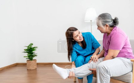 Foto de Physical therapist Asian woman, doing leg physiotherapy for elderly woman, to treat osteoarthritis and nerve pain in the leg, to nursing home and health care concept. - Imagen libre de derechos