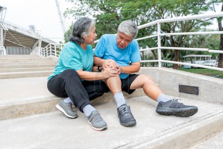 Téléchargez les photos : Couple âgé asiatique, femme touche et regarde le genou de son mari, qui est des blessures de l'exercice. aux personnes âge de la retraite et l'arthrose concept. - en image libre de droit