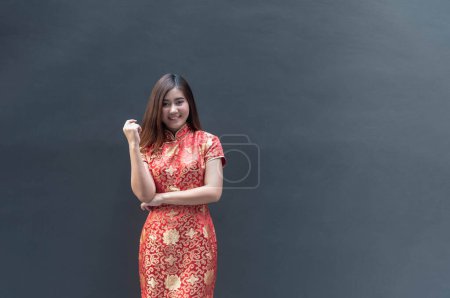 Photo for Portrait of a beautiful Asian woman wearing a red cheongsam with a concrete wall background according to the concept of Chinese girls - Royalty Free Image