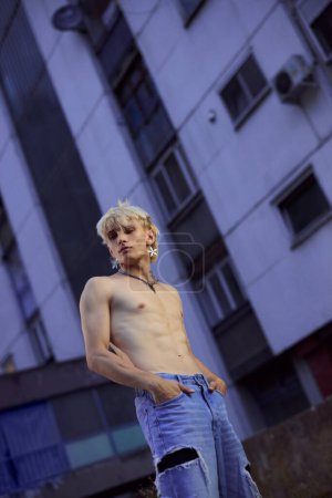 Portrait of a blonde shirtless teenage boy in the urban exterior.