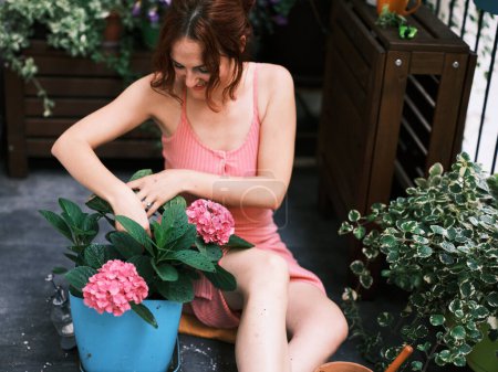 Téléchargez les photos : Une femme jardinière de plantes sur un balcon, nourrissant la vie verte dans un environnement urbain - en image libre de droit