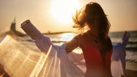 Foto de Esta vibrante imagen cuenta con una mujer silueta bailando alegremente en la playa al atardecer, irradiando energía - Imagen libre de derechos