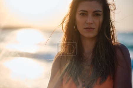Téléchargez les photos : Le regard intense de la femme avec le beau coucher de soleil et l'océan bokeh en arrière-plan - en image libre de droit