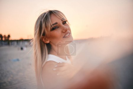 Téléchargez les photos : Une femme dans un moment serein, regardant la mer calme pendant un coucher de soleil apaisant sur une plage - en image libre de droit