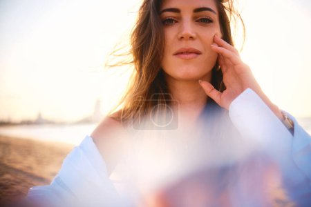 Weiche Fokusaufnahme einer nachdenklichen Frau am Strand, die in goldenes Sonnenuntergangslicht getaucht ist
