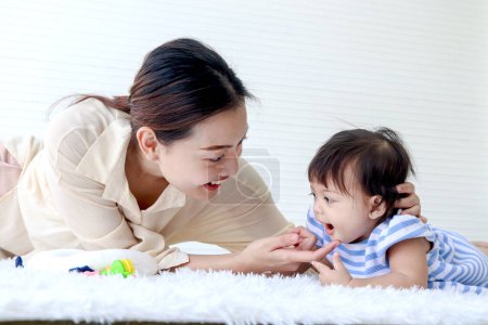 Photo for Happy toddle baby kid and mother sit on fluffy white rug floor in living room, little girl daughter and mom play with toys together, parent take care, look after infant child at home, love in family. - Royalty Free Image