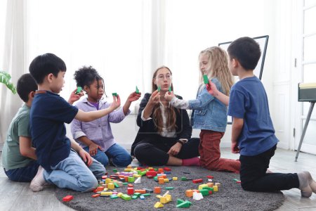 Photo for Group of primary school children study and play together in classroom with teacher, diverse students sit on floor while do activities and have fun, kid education, variety and diversity classroom. - Royalty Free Image