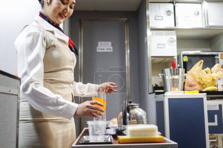 Téléchargez les photos : Belle hôtesse de l'air asiatique femme de cabine préparant la nourriture et les boissons pour servir les passagers dans l'avion, agent de bord travaillant, emploi de service aérien, voyager avec le transport aérien. - en image libre de droit