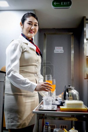 Téléchargez les photos : Belle hôtesse de l'air asiatique femme de cabine préparant la nourriture et les boissons pour servir les passagers dans l'avion, agent de bord travaillant, emploi de service aérien, voyager avec le transport aérien. - en image libre de droit