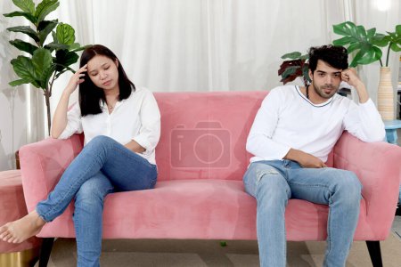 Upset disappointed couple in living room, lover have a quarrel and sitting separated on the sofa after fight, waiting other for apology. Unhappy couple after quarrel, relation problem.