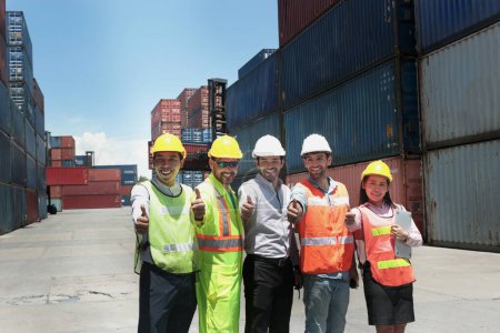 Group of worker team with helmet and safety vest stand in line and give thumbs up at logistic shipping container yard. Woman and men workmate engineers working together at workplace.