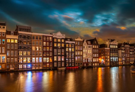 Foto de Casas típicas en el Damrak por la noche, en Amsterdam, Países Bajos - Imagen libre de derechos