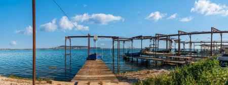 Téléchargez les photos : Un bateau à huîtres amarré sur un ponton, sur l'Etang de Thau et en arrière-plan le Mont-Saint-Clair, en Occitanie, dans le sud de la France - en image libre de droit