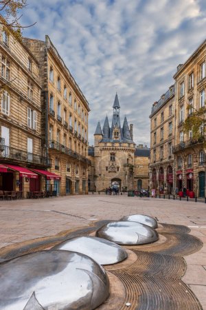 Foto de 30 de enero de 2016: Escultura en la plaza del Palacio y la Puerta de Cailhau al fondo, en Burdeos, en Gironda, en Nouvelle-Aquitania, Francia - Imagen libre de derechos