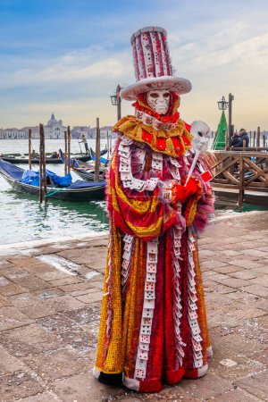 Photo for A person dressed for carnival in front of the gondolas and the Venetian lagoon in Veneto, Italy - Royalty Free Image