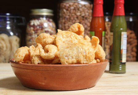 Photo for Fried Pork Rinds With Hot Sauce in Rustic Kitchen - Royalty Free Image