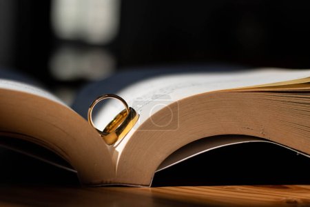 Photo for Two wedding rings are placed on the open Bible placed on the table as wedding rings prepared for lovers to wear and read Bible passages as a promise to each other. Copy Space for text - Royalty Free Image