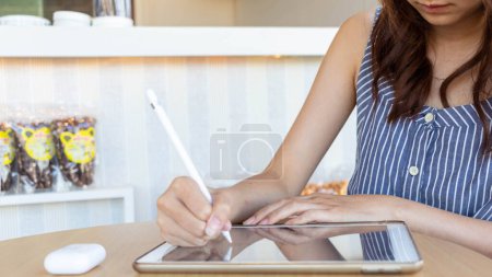 Photo for Young woman holding a stylus in her hand to use along with application in tablet to test and develop ux ui system and to design application that can work efficiently with perfect ux ui system. - Royalty Free Image