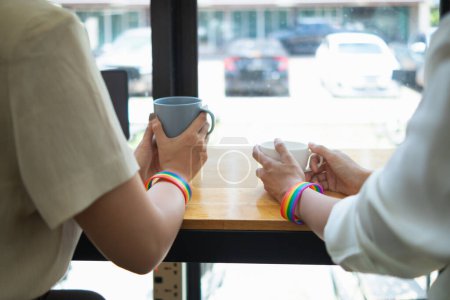 Photo for Young woman lgbtq couple is having coffee at window counter inside coffee shop and chatting happily.  concept of gender equality for lgbt Q group that can live happily together as couple. - Royalty Free Image