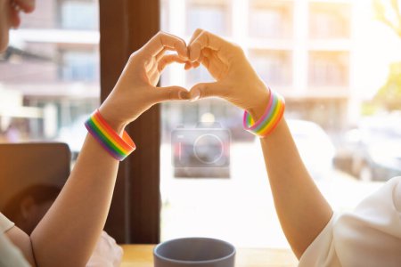 Photo for The lgbt Q couple wore lgbt Q rainbow wristbands and used their hands to form a heart symbol to symbolize friendship, love and kindness And the lgbt Q couple also promised to love each other forever. - Royalty Free Image