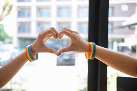 Photo for The lgbt Q couple wore lgbt Q rainbow wristbands and used their hands to form a heart symbol to symbolize friendship, love and kindness And the lgbt Q couple also promised to love each other forever. - Royalty Free Image