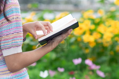 Photo for Young woman holding up a Bible to read because she wants to learn the teachings of God from the Bible with faith and faith in God. The concept of learning the teachings of God from the Bible. - Royalty Free Image
