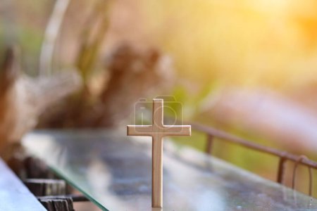 Photo for Cross representing God in Christianity is placed on mirror and its reflection can be seen on blurred background of nature. cross on background is blurred and there is Copy Space on side for text. - Royalty Free Image
