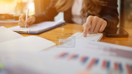 Photo for An accountant is using a calculator to accurately calculate the income and expenses and is using the calculator to review the company investment results and profits Copy Space for text - Royalty Free Image