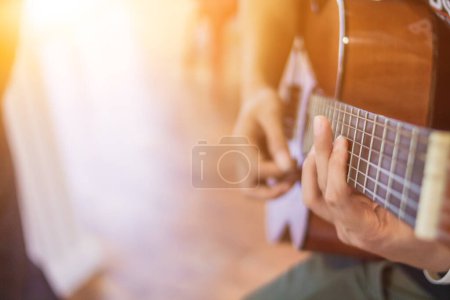 Téléchargez les photos : Un jeune homme s'entraîne à jouer de la guitare dans une salle de pratique musicale avant de se produire afin de réduire l'erreur de jouer de la guitare sur scène. Close Up Jeune homme tient des accords de guitare pour la pratique. - en image libre de droit