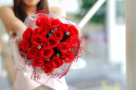 woman holds bouquet of red roses in her hand after receiving one from her boyfriend on Valentine's Day to show his love for woman. sending bouquet of roses to your lover to express your love for each