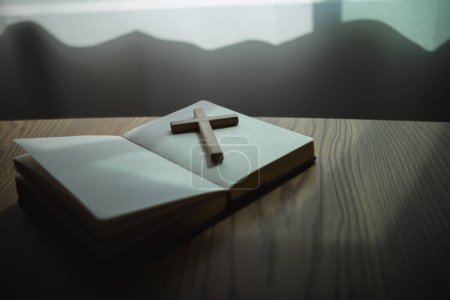 cross is placed on the Bible after prayer to God, which is religious ritual of Christianity and belief in the teachings of God. concept of praying to God with the teachings of the Bible and cross.