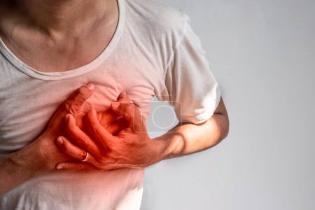 Photo for Asian young man suffering from left sided chest pain. Chest pain can be caused by heart attack, myocardial infarct or ischemia, myocarditis, pneumonia, stress, etc. - Royalty Free Image