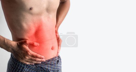 Photo for Asian young man suffering from abdominal pain. It can be caused by stomach ache, enteritis, colitis, appendicitis, hepatitis, pancreatitis, food poisoning, etc. - Royalty Free Image