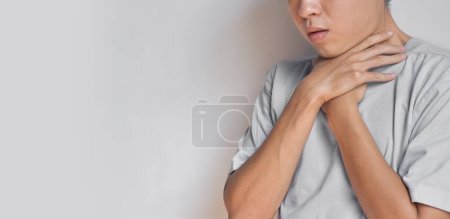 Téléchargez les photos : Tightness at the neck of Asian, Myanmar man. Concept of sore throat, pharyngitis, laryngitis, esophagitis, thyroiditis, dysphagia, choking or gasping. - en image libre de droit