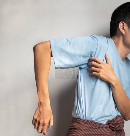 Téléchargez les photos : Stiffness in the shoulder joint of Southeast Asian young man. Concept of frozen shoulder or arm muscle power problems. - en image libre de droit