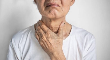 Enge am Hals eines älteren asiatischen Mannes. Konzept von Halsschmerzen, Rachenentzündung, Kehlkopfentzündung, Ösophagitis, Thyreoiditis, Thyrotoxikose, Dysphagie, Ersticken oder Keuchen.