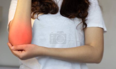 Photo for Pain in the elbow joint of Asian young woman. Concept of elbow pain, injury, rheumatism or osteoarthritis. - Royalty Free Image