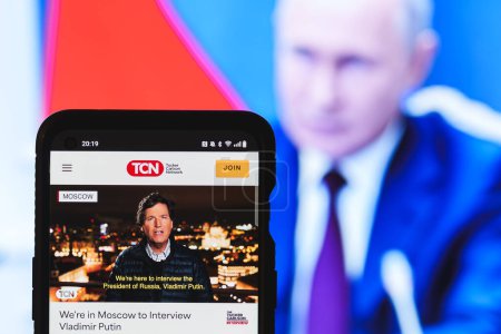 Foto de Moscú, Rusia - 2024 7 de febrero: Tucker Carlson media network website on smartphone screen. Vladimir Putin en segundo plano. Foto de alta calidad - Imagen libre de derechos