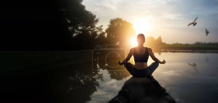 Foto de Woman practices yoga and meditation of serenity on the sunset nature background. - Imagen libre de derechos