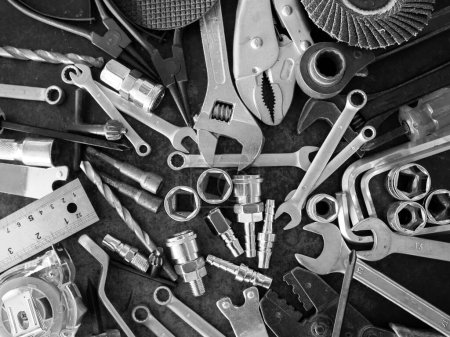 Handwerkzeuge bestehend aus Schraubenschlüssel, Zange, Steckschlüssel, ausgelegt auf altem Stahlblechhintergrund.
