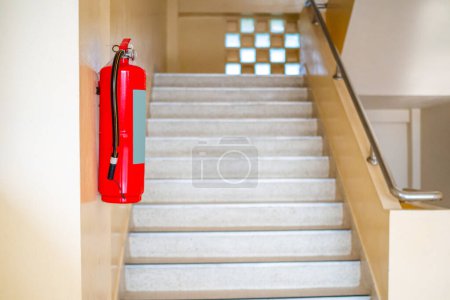 Foto de Un extintor de incendios cuelga las escaleras. Concepto de seguridad contra incendios. - Imagen libre de derechos