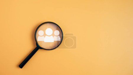 Téléchargez les photos : Les icônes du groupe de clients dans une loupe placée sur un fond jaune représentent la sélection des objectifs commerciaux, les clients cibles. Plans et stratégies marketing, stratégies centrées sur le client. - en image libre de droit