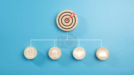 Circular wood with printed target icons and business symbols on light blue background, business goals and objectives concept, business competition, Customer relationship management concept.