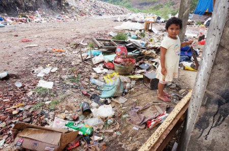 Téléchargez les photos : Sangatta, East Kalimantan / Indonésie - 03 août 2020 : Une enfant non identifiée est debout alors que ses parents travaillent sur un dépotoir. - en image libre de droit