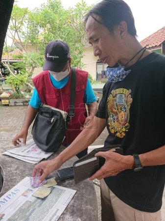 Foto de Photo editorial, 10 december 2022, man buy newspaper from old seller, yogyakarta yogya jogja jogjakarta, indonesia - Imagen libre de derechos